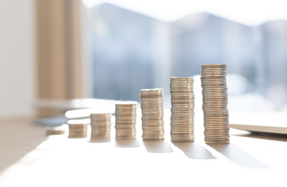 pay rates. silver coins stacked in piles in front of a sunny window