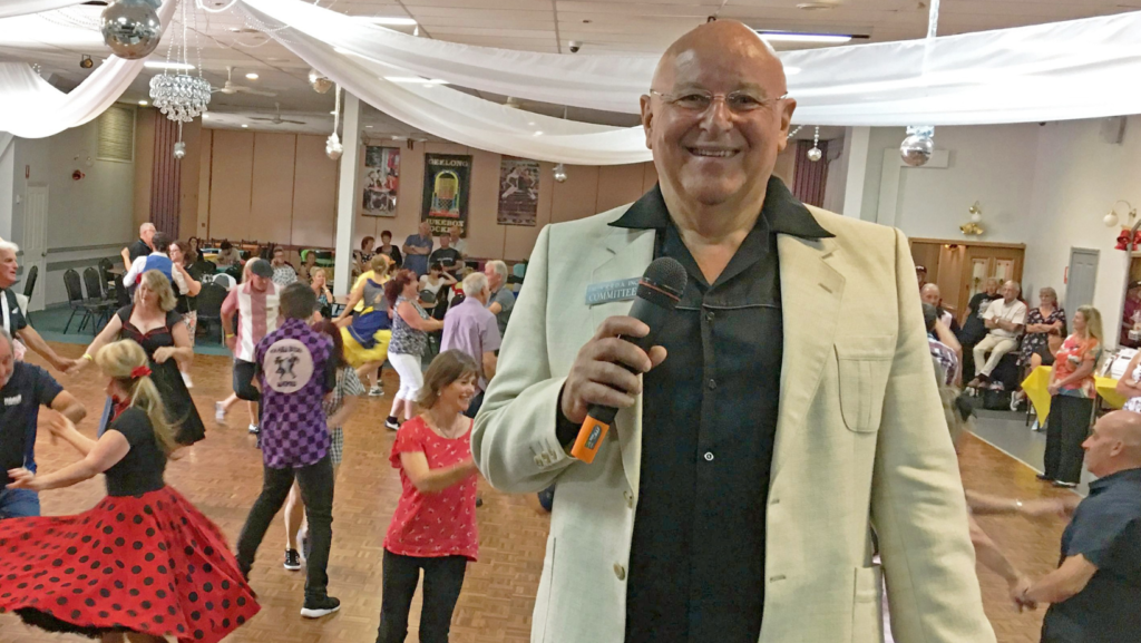 Rob Ewart, President of the Victorian Rock'n'Roll Association at the 2019 Geelong Competition with dancers in the background