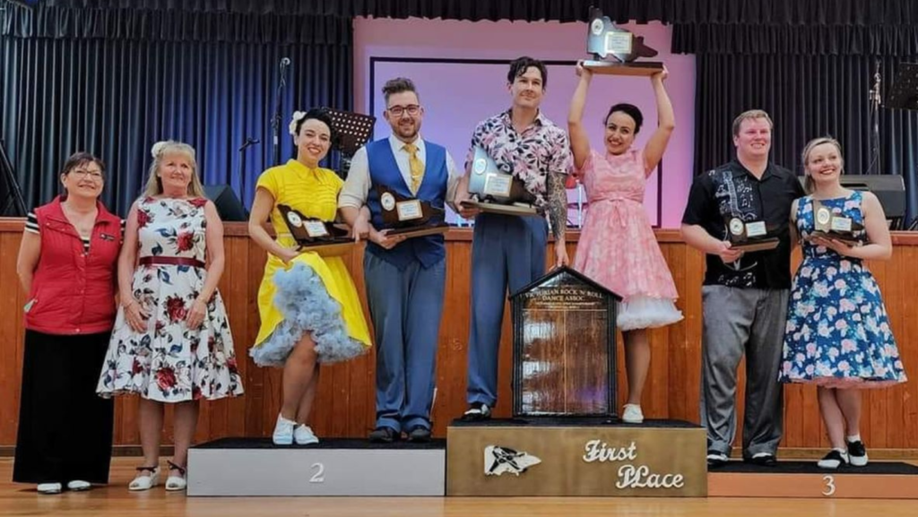 Winners of the 2022 Victorian Rock'n'Roll Dance State Championships standing on the podium holding trophies